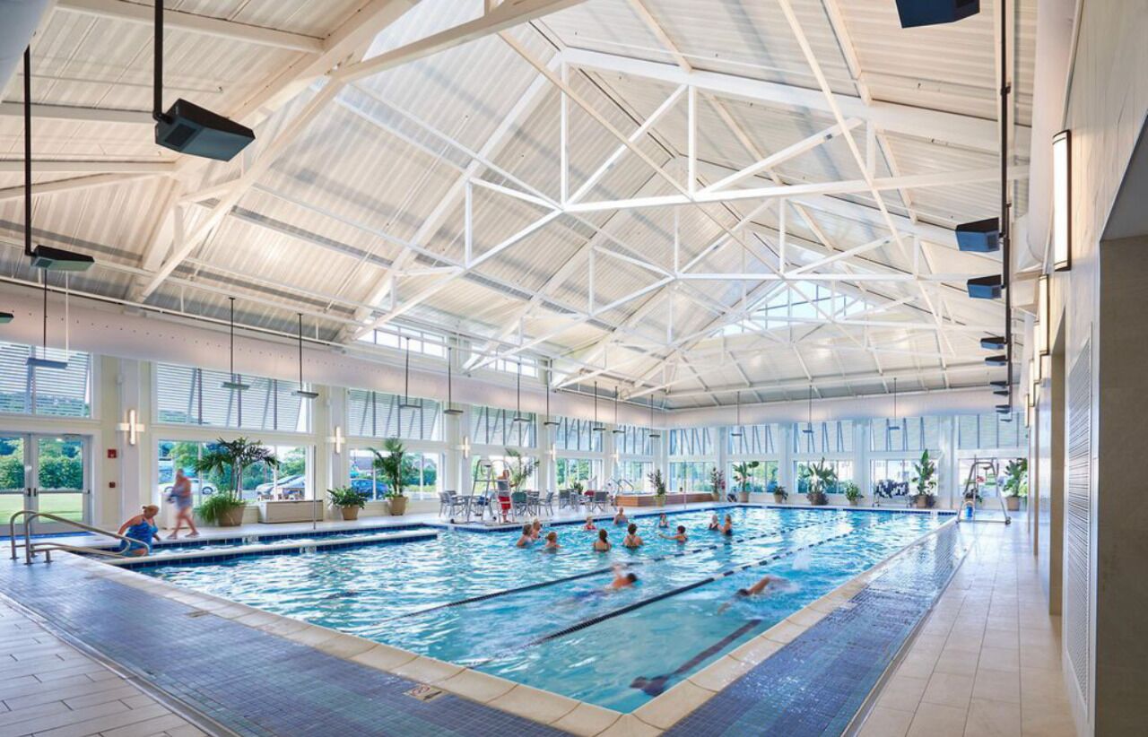 Una piscina interior con techos altos y ventanas amplias.