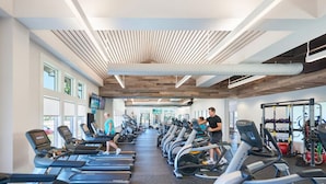 Un gimnasio con cintas de correr, bicicletas estáticas y máquinas de pesas.