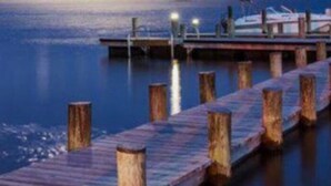Un muelle de madera que se adentra en aguas tranquilas, con un barco amarrado al final.