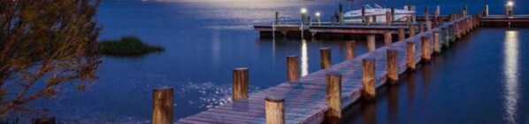 A wooden pier extending into calm water with a boat docked at the end.