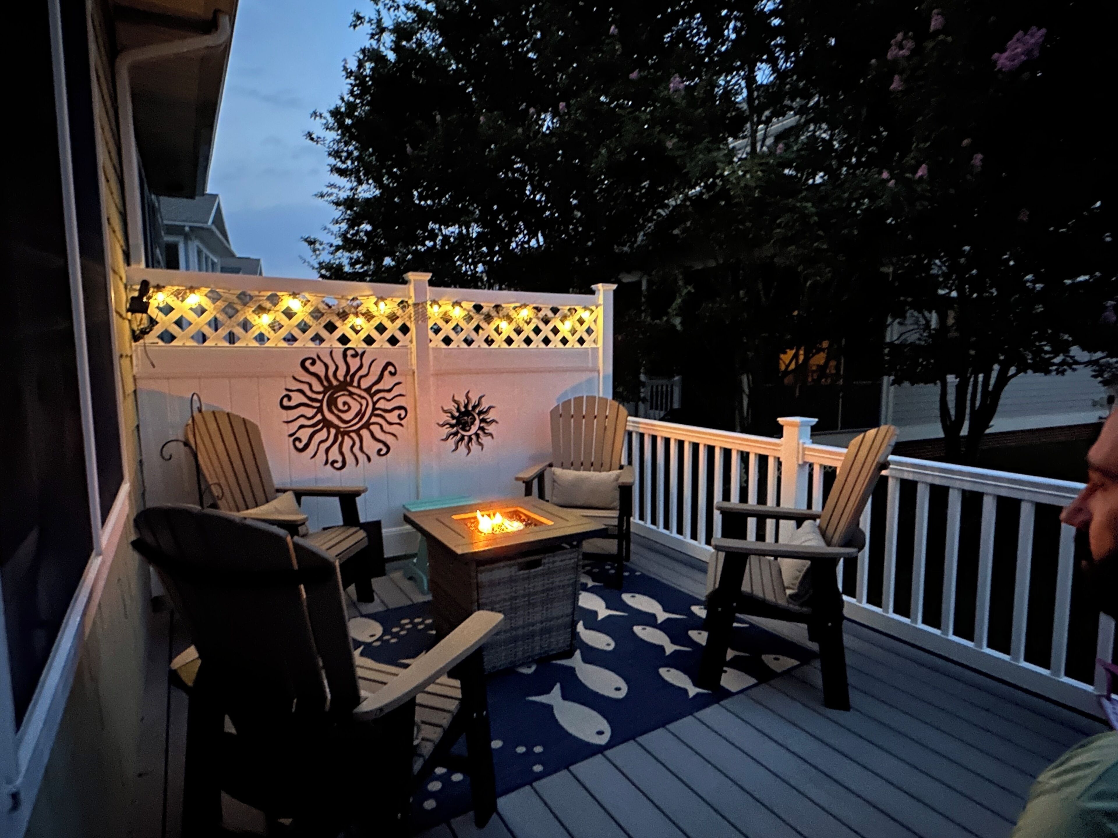 A deck with outdoor seating, a fire pit, and decorative sun motifs on the wall.