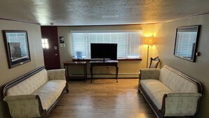 Una sala de estar con dos sofás, un televisor y una lámpara.