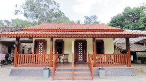 A two-story building with a tiled roof, a porch with wooden railings, and a door with a decorative pattern. - Homestay Nike Bed (Borobudur)
