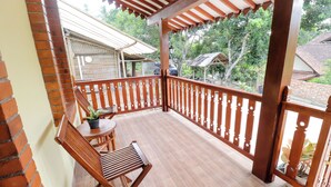A wooden balcony with a tiled floor, a wooden chair, and a small table with a potted plant. - Homestay Nike Bed (Borobudur)
