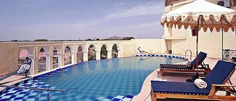 Een buitenzwembad, parasols bij het zwembad en ligstoelen