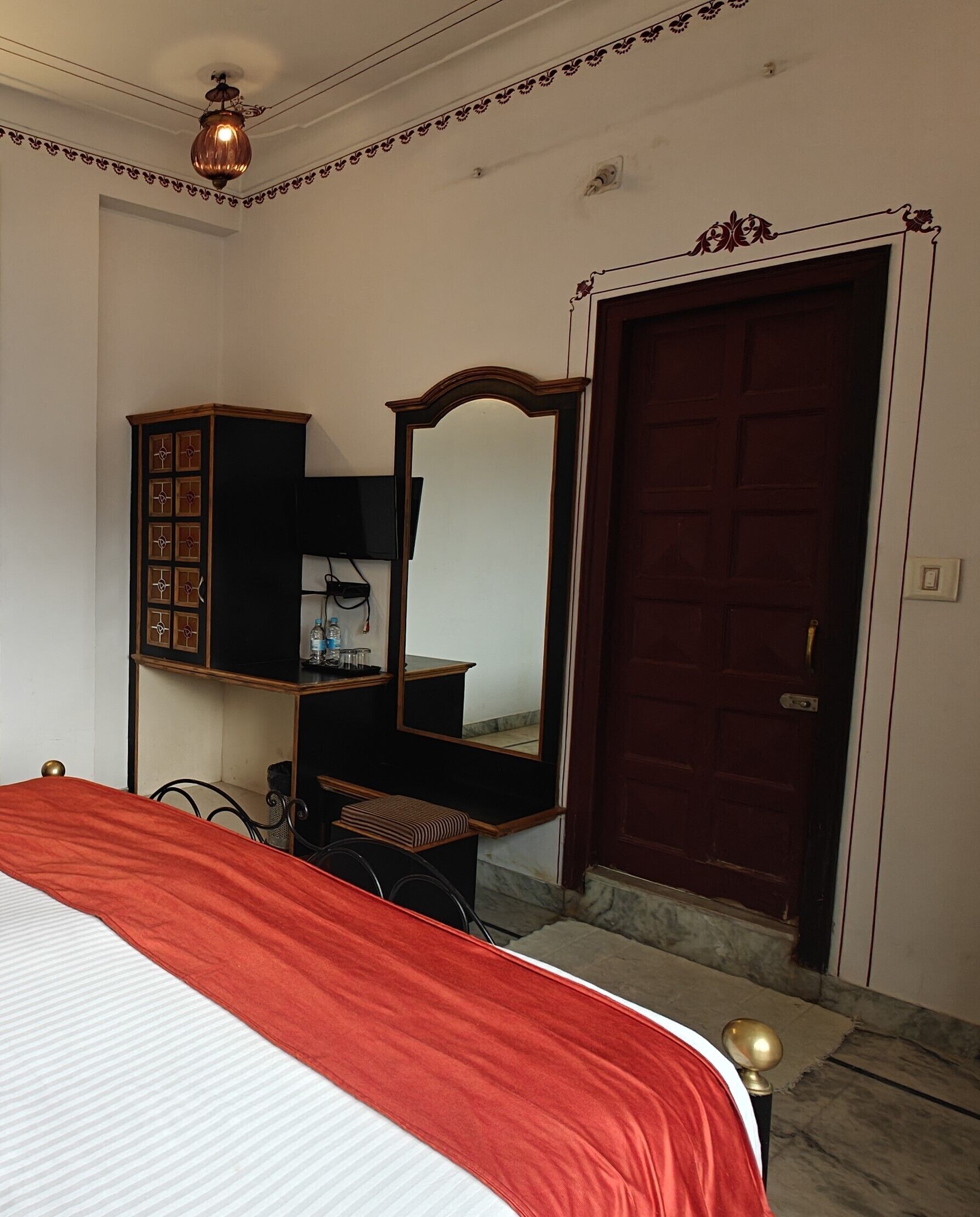 Een slaapkamer met een bed, een kaptafel, een spiegel en een deur.