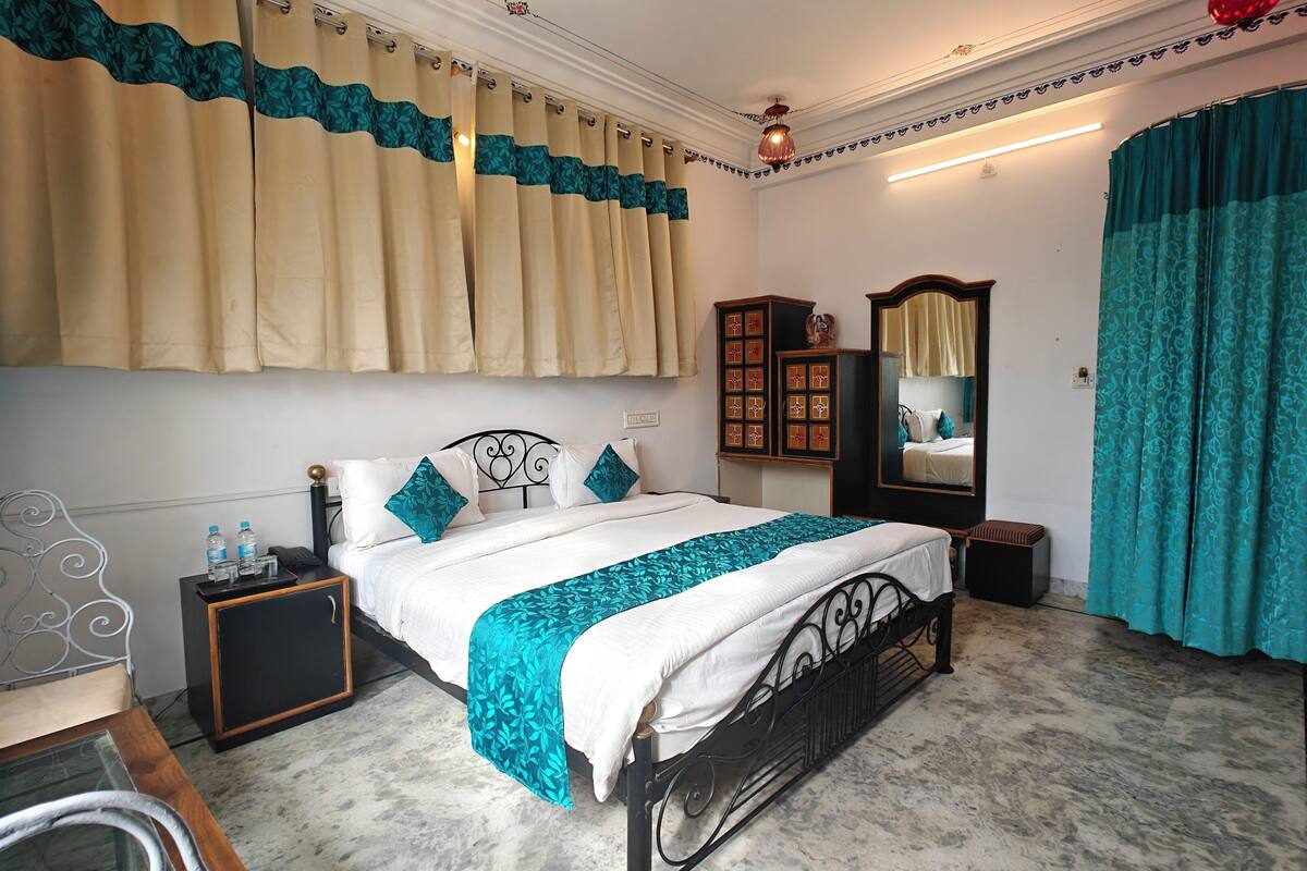 A neatly arranged bedroom with a bed, bedside tables, a mirror, and curtains.