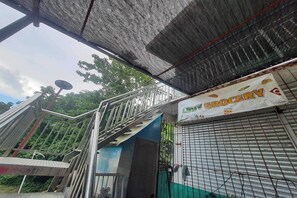 A staircase leading to a building with a 'GROCERY' sign, a metal gate, and a partially visible tree.