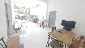 A spacious room with a wooden table and chairs, a television, and a water dispenser.
