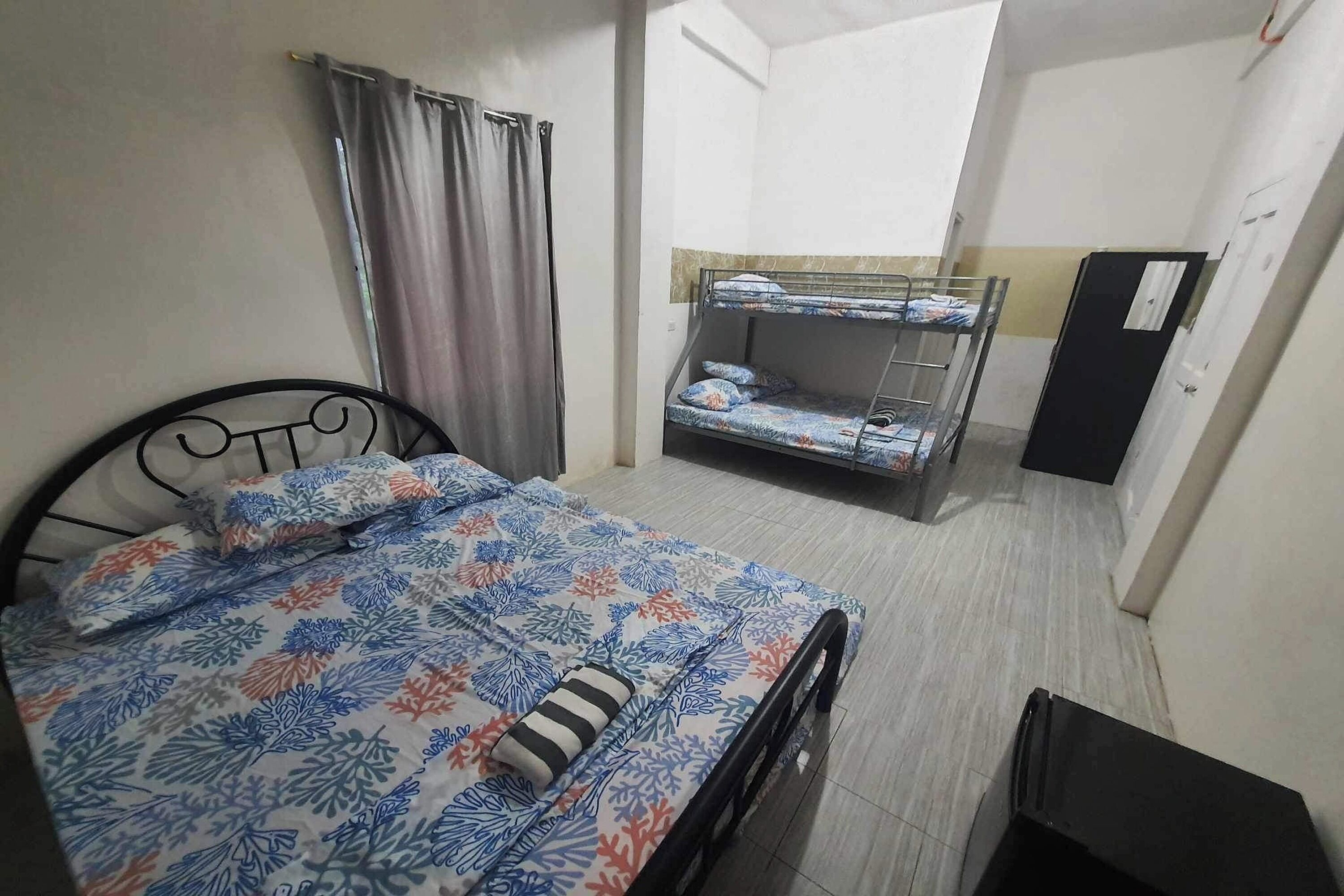 A room with a single bed, a bunk bed, a desk, and a wardrobe.