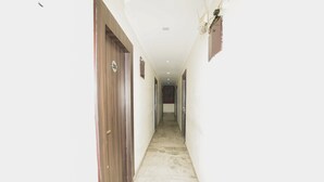 Un pasillo estrecho con puertas de madera a un lado y piso de baldosas.