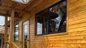 A wooden cabin with a porch, a door, and a window. - Skema Collections Quito (Conocoto)