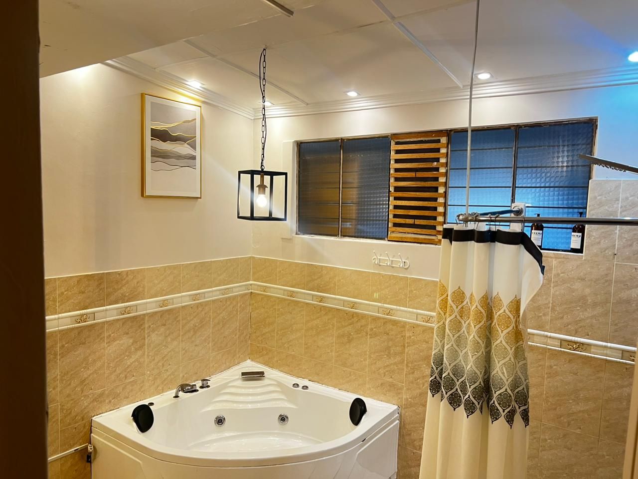 Ein modernes Badezimmer mit einer großen Badewanne, einer Duschvorhang und einem Fenster mit Jalousien.