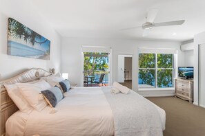 Ein geräumiges Schlafzimmer mit einem großen Bett, einem Deckenventilator und einem Balkon mit Meerblick.