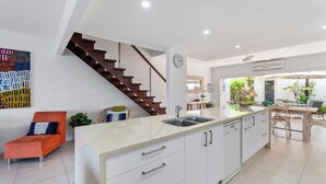 Une cuisine moderne dotée d’un îlot central, de meubles blancs et d’une cuisinière intégrée.