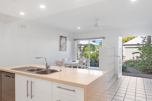 Enjoy meals in the kitchen with a central island, sink, and dishwasher, adjacent to a dining area with a table and chairs.