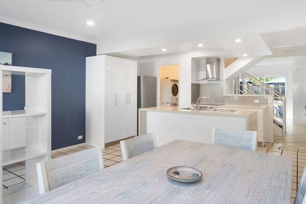 Kitchen area with central island, sink, and stove, plus dining table and chairs.