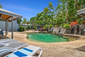 Relax by the pool surrounded by a natural rock formation and lush greenery.