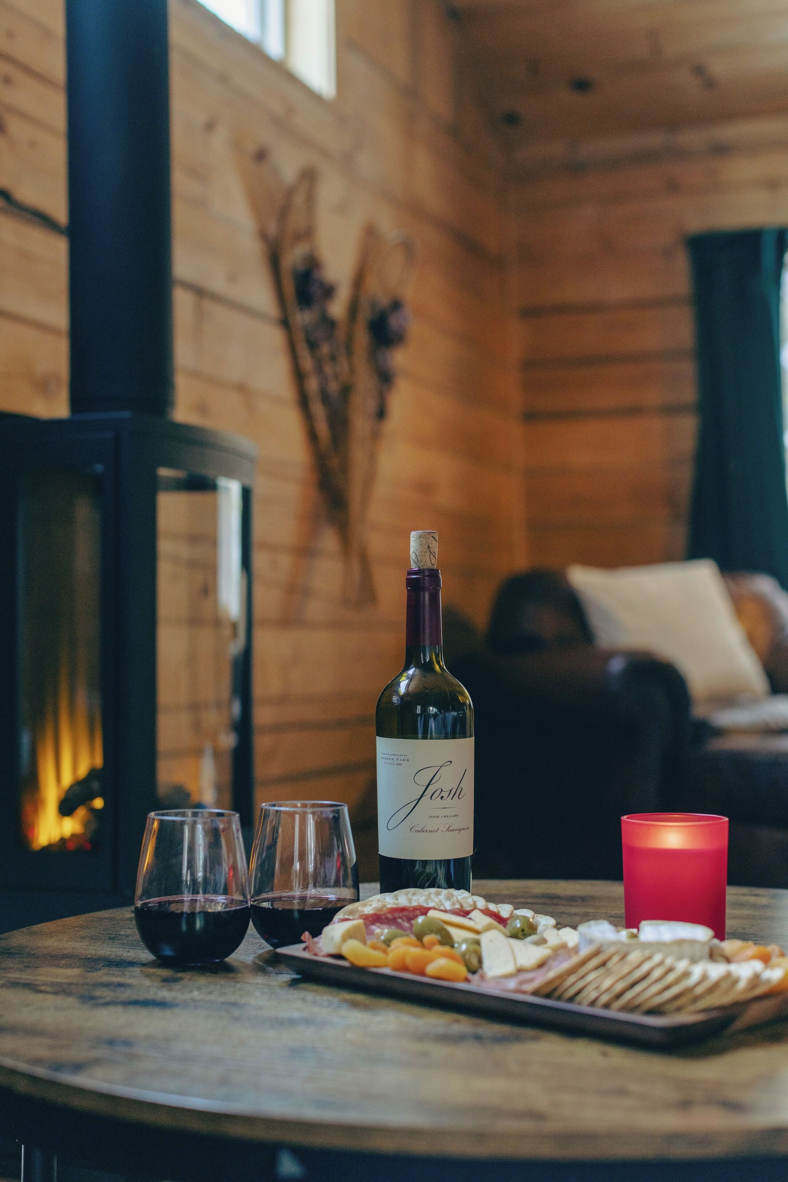 A wooden interior with a table set for a meal, a bottle of wine, and glasses.