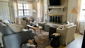 A living room with a fireplace, sofas, a coffee table, and a television mounted on the wall.