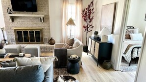 A modern living room with a fireplace, a sofa, a coffee table, and a TV mounted on the wall.