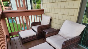 Un patio couvert avec des meubles en osier et une terrasse en bois.