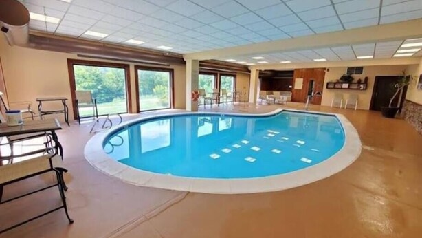 Une piscine intérieure avec un sol carrelé, une table de billard et un espace bar.