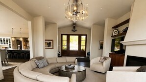 A spacious living room with a large L-shaped sectional sofa, a round coffee table, and a fireplace.
