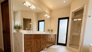 A modern bathroom with a large vanity, a walk-in shower, and a glass-enclosed shower area.