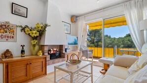 A cozy living room with a fireplace, a sofa, a coffee table, and a view of the outdoors. - Apartment with parking 400m beach and shops (Calella de Palafrugell)