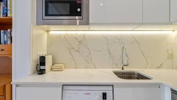 Een moderne keuken met een ingebouwde magnetron, een Bosch vaatwasser en een marmeren spatwand.