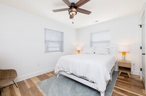 A bedroom with a bed, two bedside lamps, a ceiling fan, and a wicker chair. - Private Island! Includes 2 houses, covered boathouse, best sunset on Indian Lake (Washington Township)