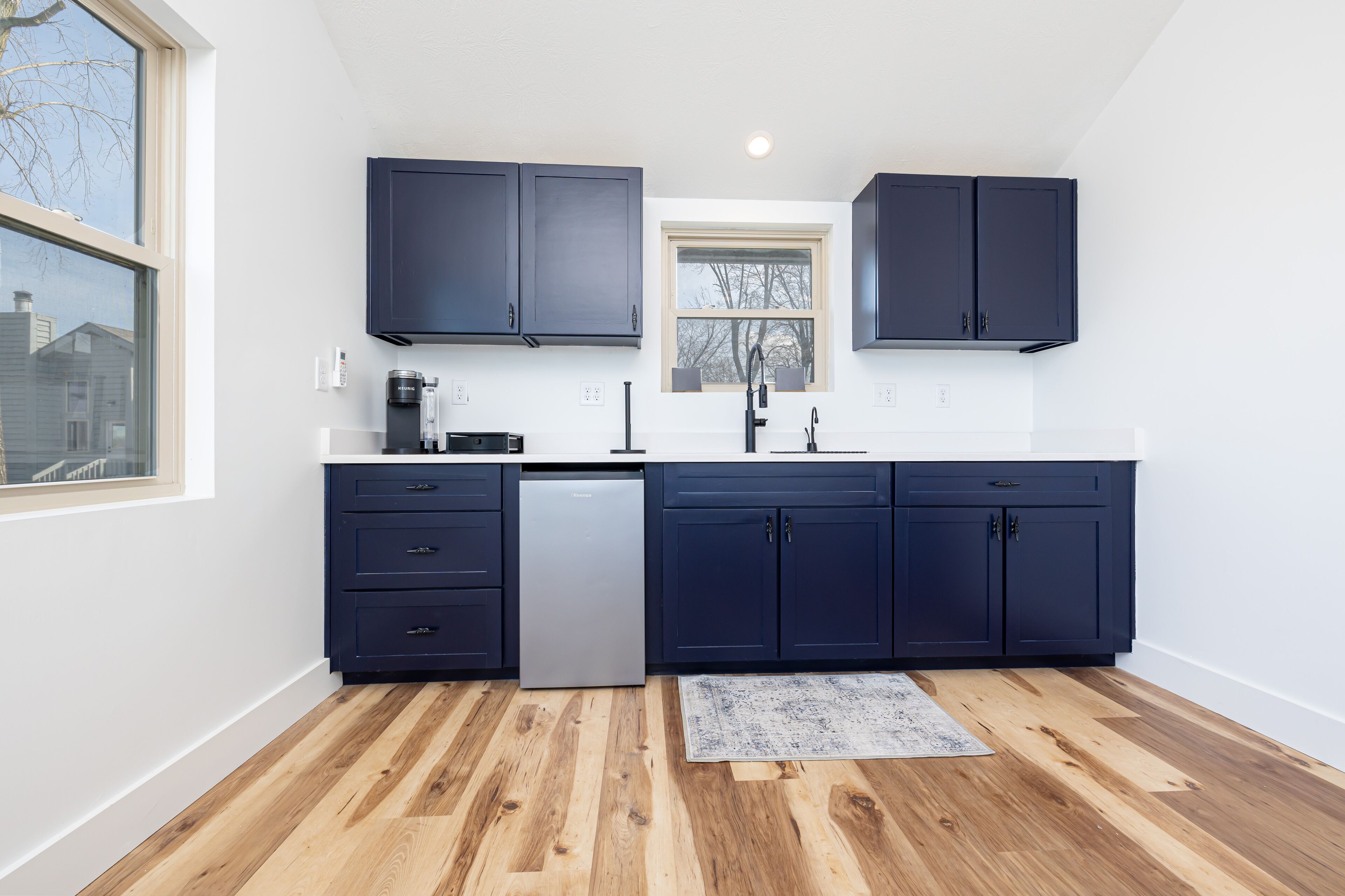 A modern kitchen with dark cabinets, a dishwasher, and a window.