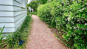 Un chemin pavé de briques mène à un bâtiment dont le revêtement extérieur est blanc.