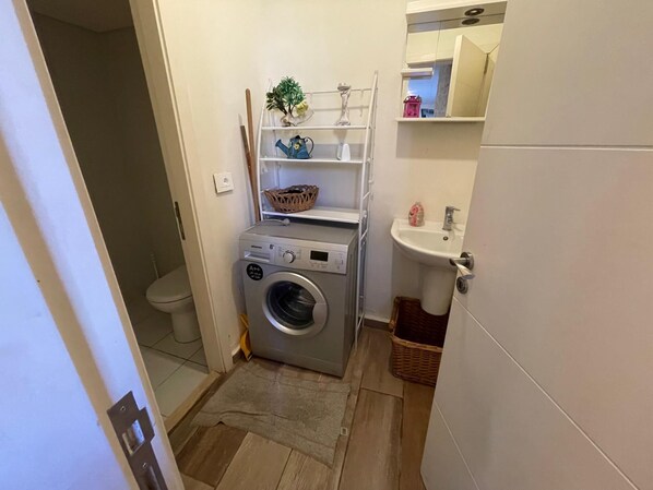 A compact bathroom with a washing machine, a sink, and a small shelf with toiletries. - Seaside Chalet Escape in Batroun (Batroun)