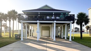 A large, single-story building with a central entrance, flanked by white columns and a covered porch area. - Cozy Beach House - short walk to the water, quiet neighborhood. (Galveston)