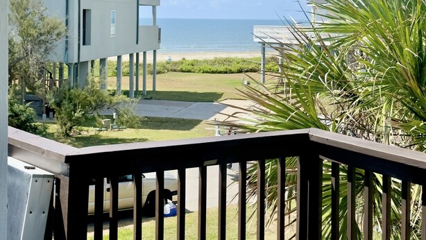 A balcony with a view of a beach and houses. - Cozy Beach House - short walk to the water, quiet neighborhood. (Galveston)