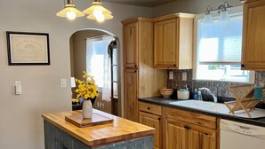 A kitchen with wooden cabinets, a stainless steel trash bin, and a built-in dishwasher. - Cozy Cottage in Downtown Redmond (Redmond)