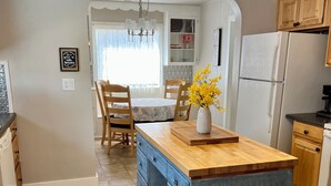 A kitchen with a central island, wooden cabinets, a refrigerator, and a dining area with chairs and a table. - Cozy Cottage in Downtown Redmond (Redmond)