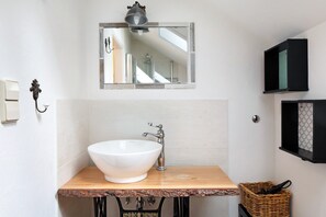 Une salle de bain avec un lavabo blanc, un plan de toilette en bois et un miroir au-dessus.
