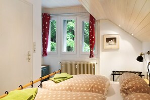 Une chambre à coucher avec un lit, un radiateur, une fenêtre avec des rideaux et un tableau encadré au mur.