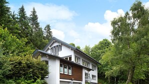 A two-story house with a garage, surrounded by dense greenery and trees. - Apartment 'Feldbergstern' with Shared Terrace and Wi-Fi (Feldberg)