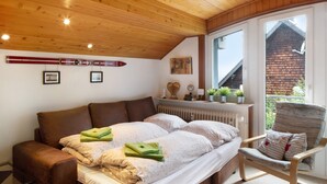A bedroom with a bed, a chair, a radiator, and a window with a view of a building. - Apartment 'Feldbergstern' with Shared Terrace and Wi-Fi (Feldberg)