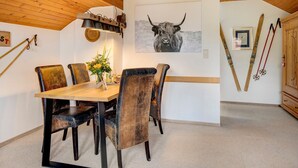 A dining area with a wooden table and chairs, a wall-mounted light fixture, a bull's head artwork, and skis leaning against the wall. - Apartment 'Feldbergstern' with Shared Terrace and Wi-Fi (Feldberg)
