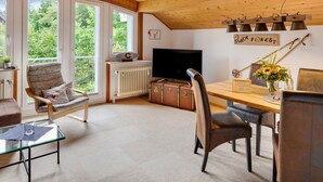 A room with a wooden ceiling, large windows, a television, a dining table, and a chair. - Apartment 'Feldbergstern' with Shared Terrace and Wi-Fi (Feldberg)