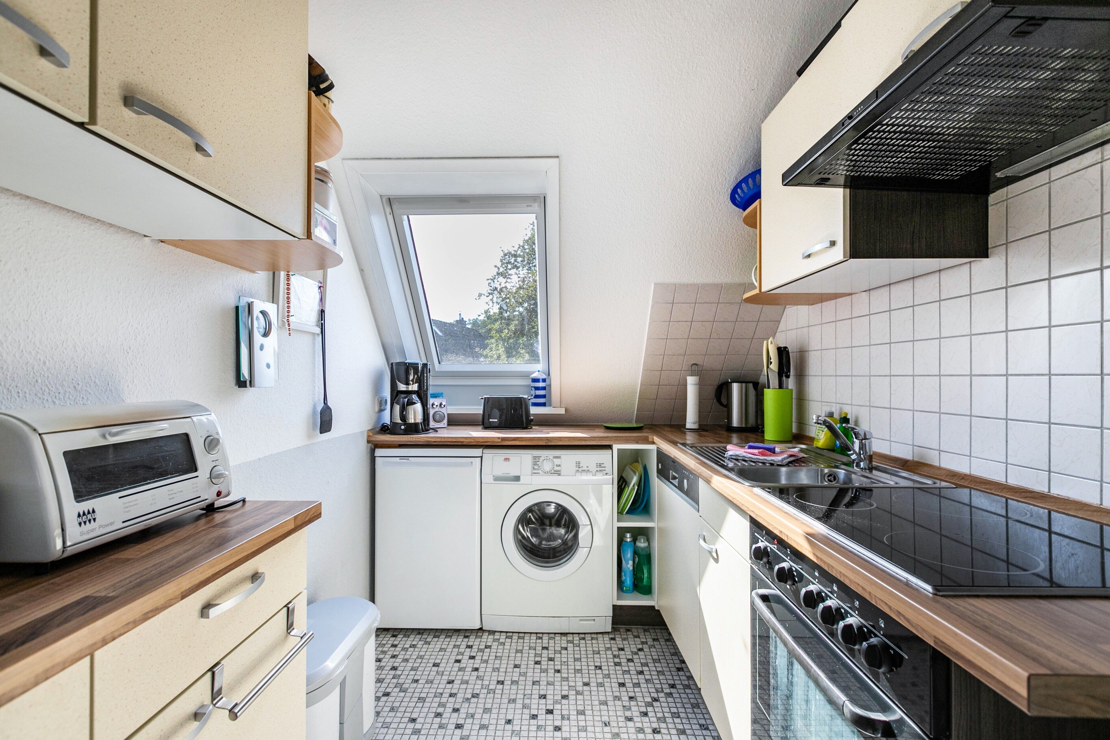 Una cocina compacta equipada con lavadora, tostadora y estufa.