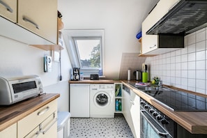 A compact kitchen with a built-in washing machine, a toaster, and a stove.