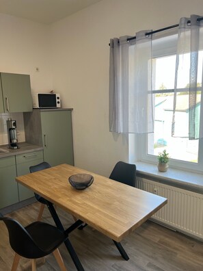 A small kitchen with a microwave, a coffee maker, and a window with a curtain. - Apartment "2 - Haus Lausitzring" with Private Terrace & Wi-Fi (Annahütte)