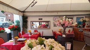 Un espace de restauration intérieur avec des tables dressées pour le service, un miroir et une horloge au mur.
