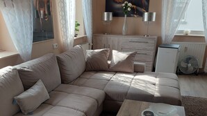 Un salon avec un canapé d’angle, une table basse en bois et un radiateur.